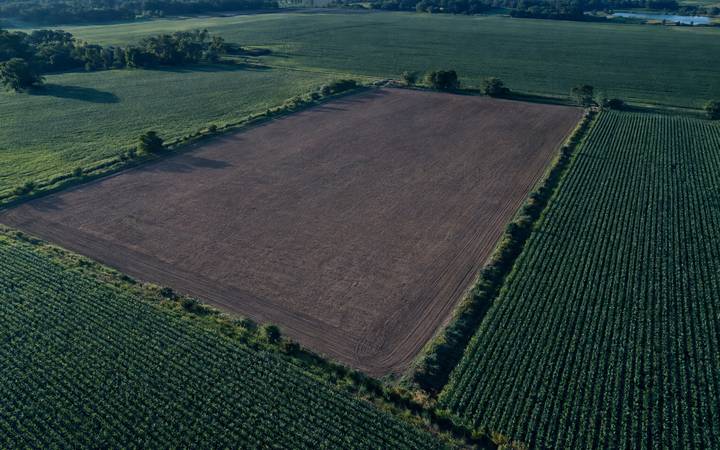 Aerial view of a bare, unplanted field surrounded by planted fields